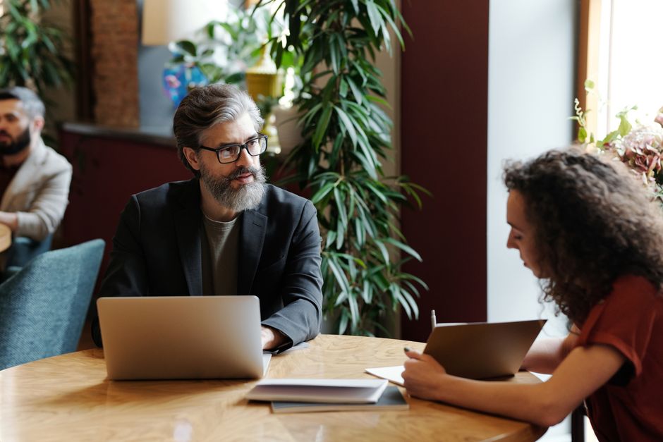Dos profesionales conversan en una cafetería con un portátil que muestra gráficos